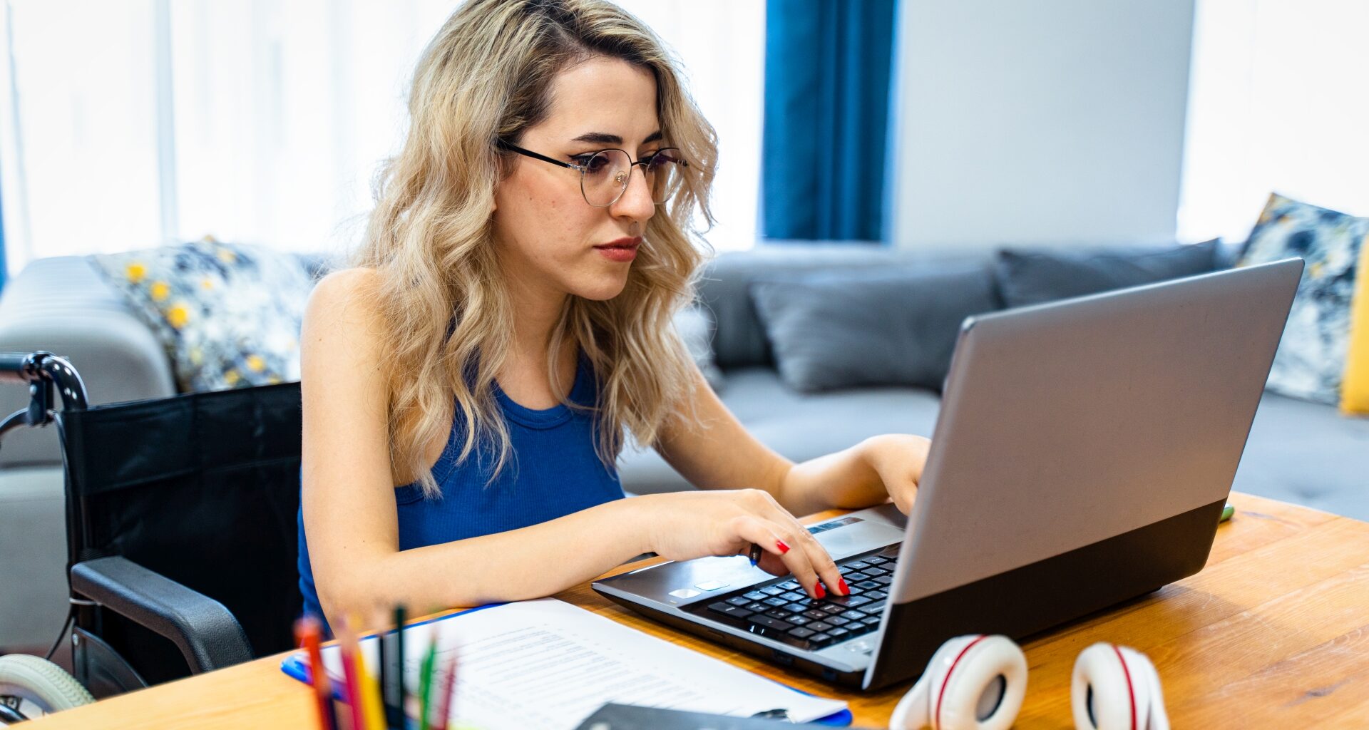 disabled woman sitting in wheelchair at the table and looking at computer monitor.