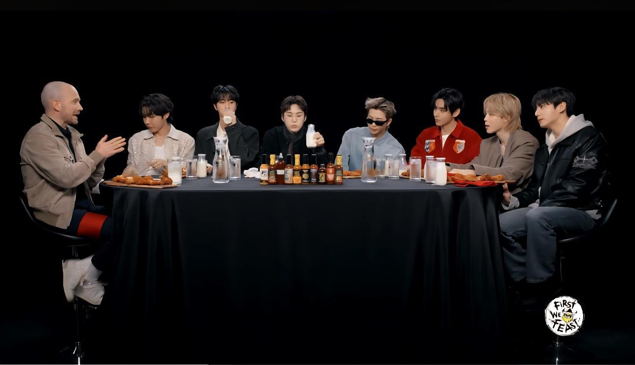 Members of BTS sit with host Sean Evans, left, during their appearance on YouTube talk show “Hot Ones,” taking on progressively spicier wings while answering questions. Captured from First We Feast YouTube Channel