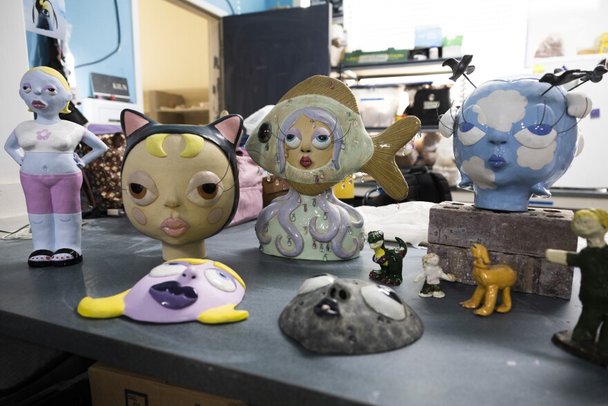 Pieces of pottery artwork, including faces, sits on a table.