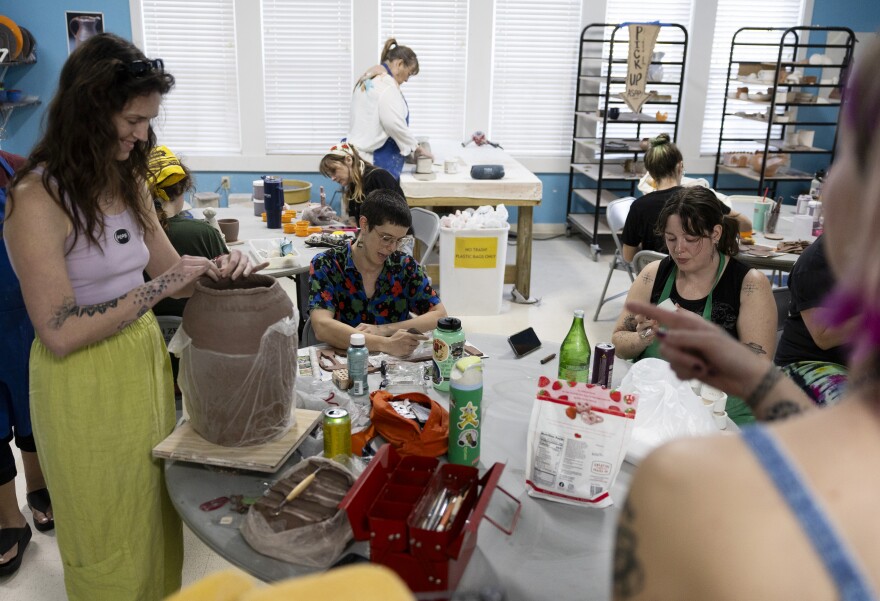 Three women work on pottery inside a pottery class.