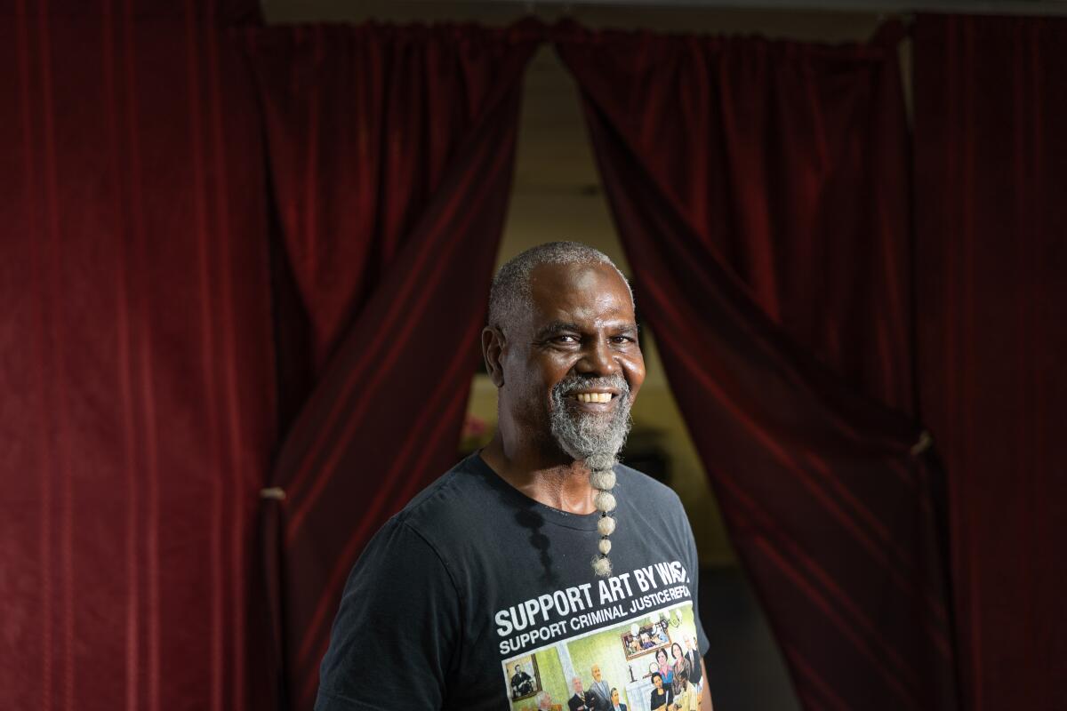 An artist by a red curtain.