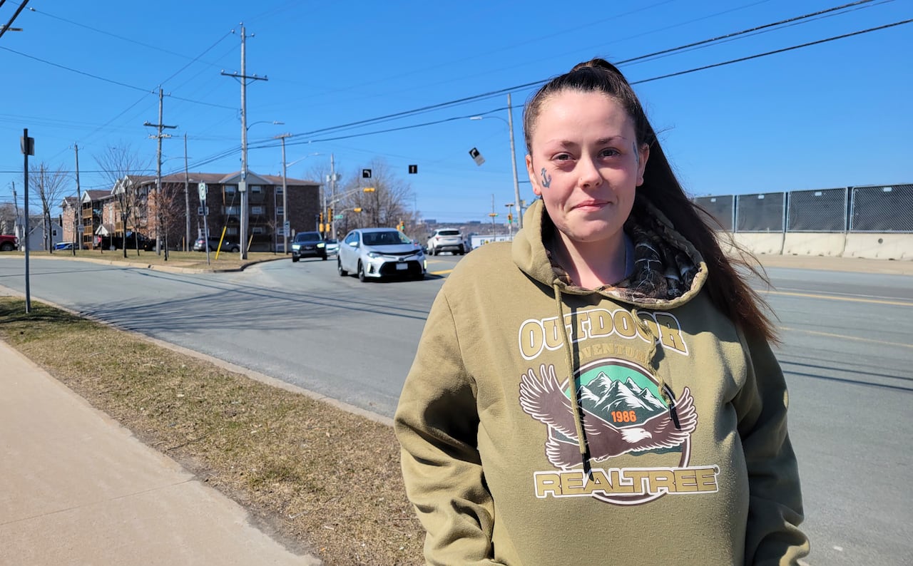 a woman stands by a road