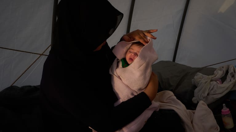 Haifa Kenjo, who fled Israeli airstrikes on the southern suburbs of Beirut, holds her 15-day-old daughter Shiman inside the tent she uses as a shelter.