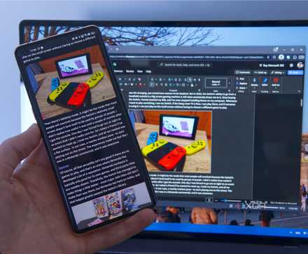 A phone running Microsoft Word with a computer in the background editing the same document