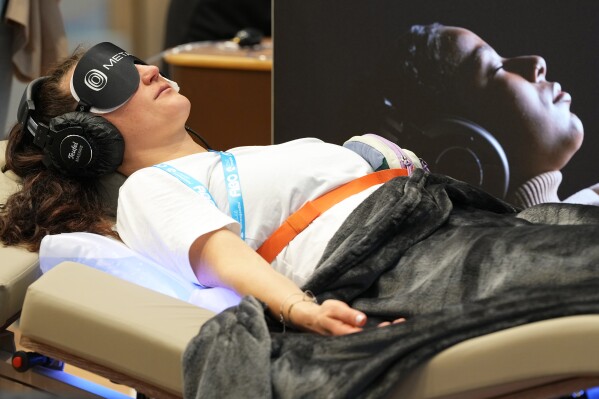 A woman relaxes on a mental fitness lounger at the health & fitness trade show FIBO in Cologne, Germany, Friday, April 17, 2026. (AP Photo/Martin Meissner)