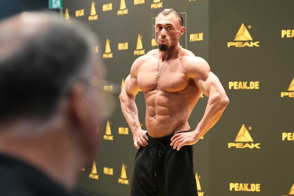A bodybuilder promotes protein food supplements at the health & fitness trade show FIBO in Cologne, Germany, Friday, April 17, 2026. (AP Photo/Martin Meissner)