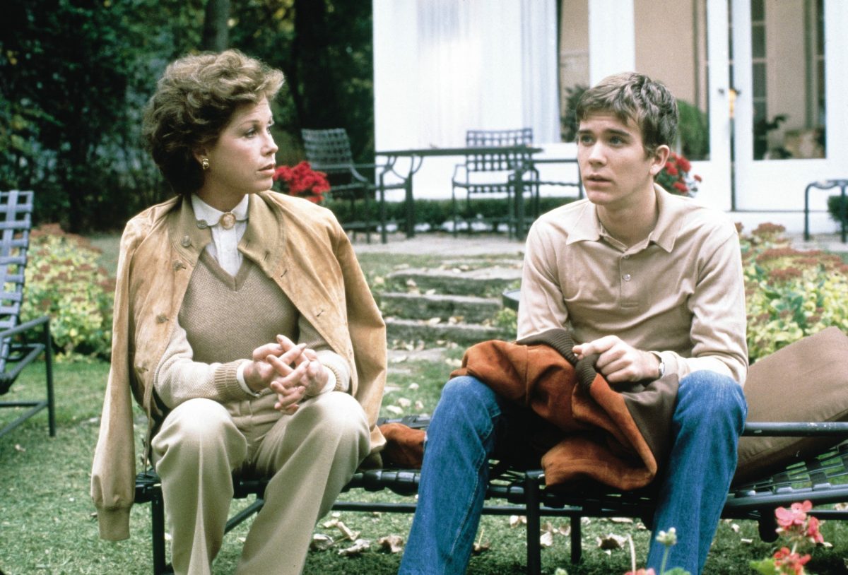 A mother and son sit outside on a bench.