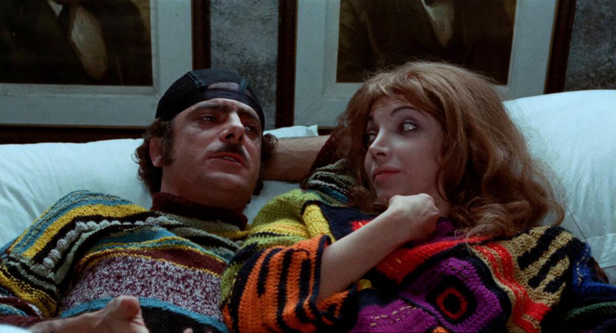 A woman and a man lean back on a couch.