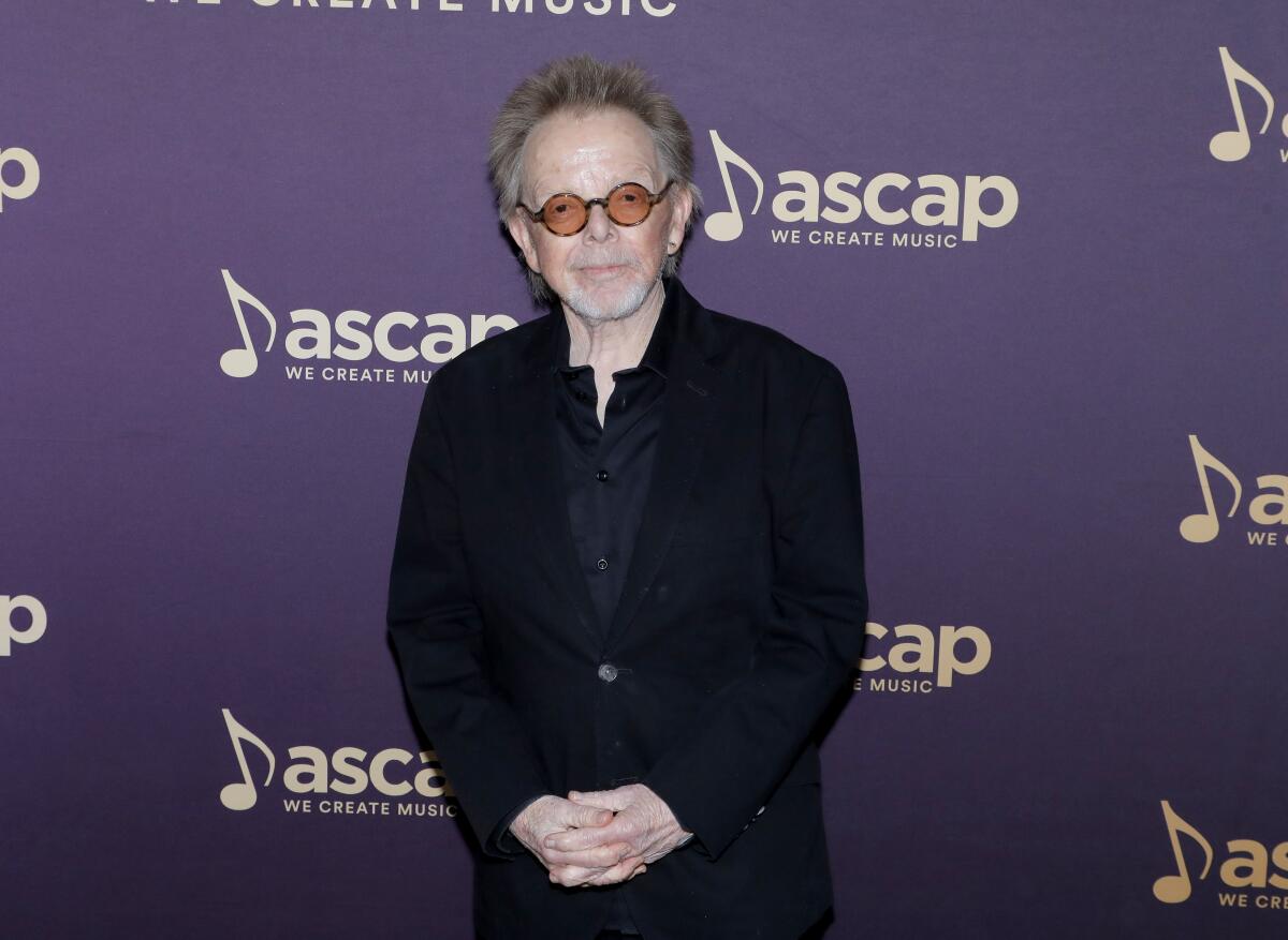 A man in sunglasses smiles for photographers at an awards show.