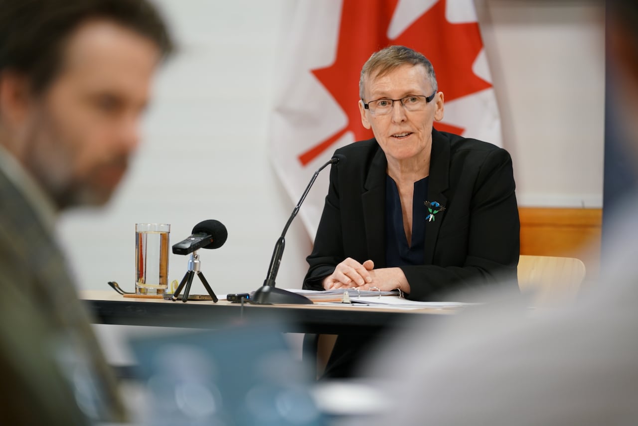 Woman in dark suit seated at a table.