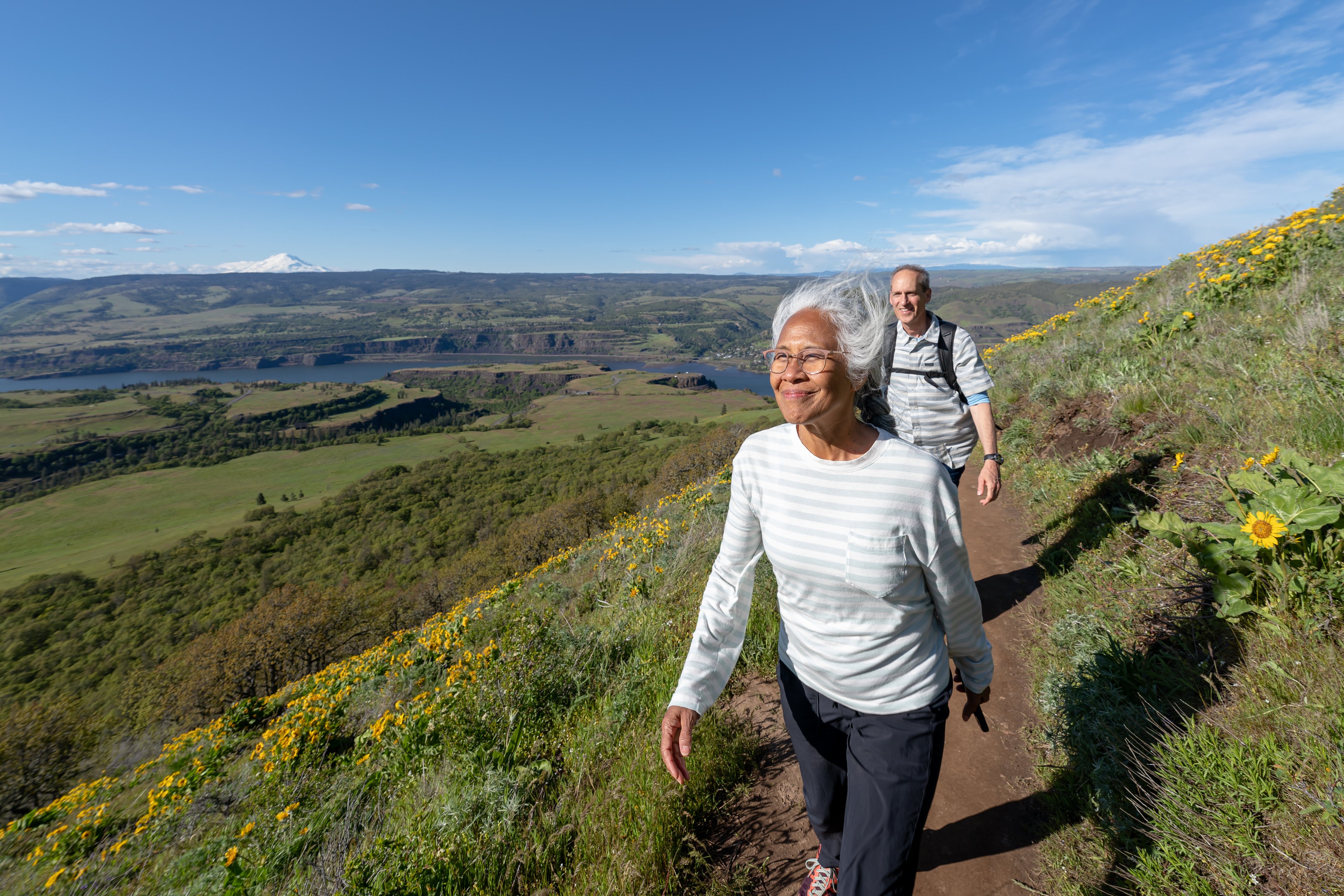 Two people outside walking on a trail.