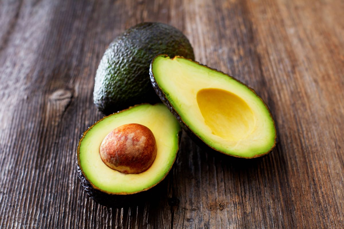 Whole and sliced avocado on wood