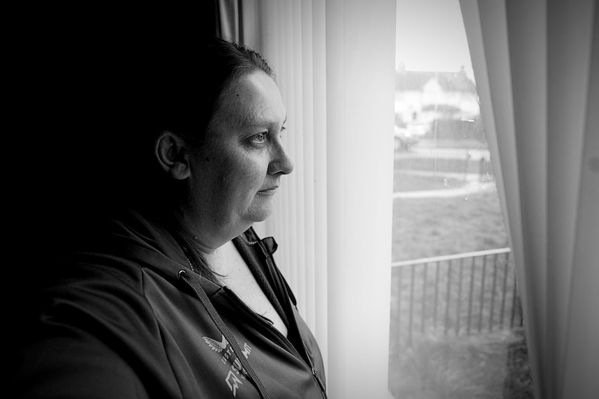 A woman looking out a window at home.