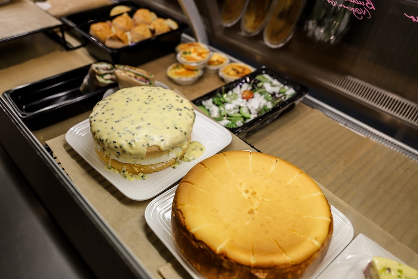 Two cakes sit in display window at a cafe amid other food items