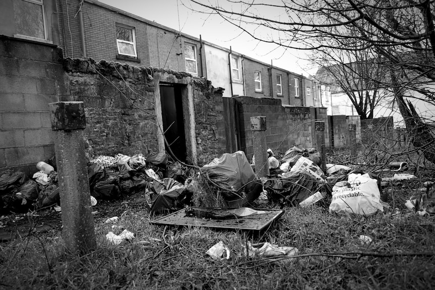 Large rubbish bags outside a row of houses.