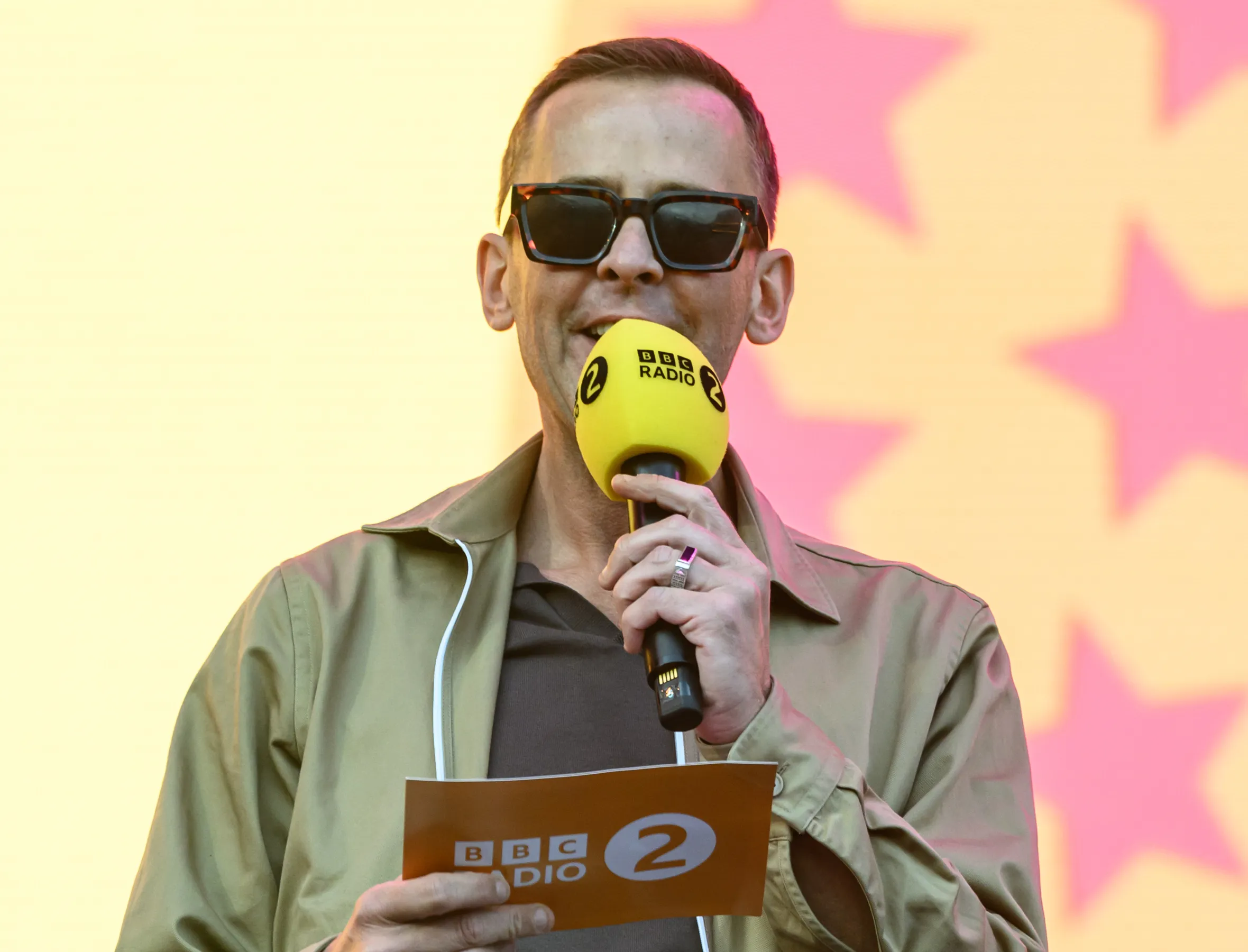 Scott Mills onstage with a BBC Radio 2 microphone.