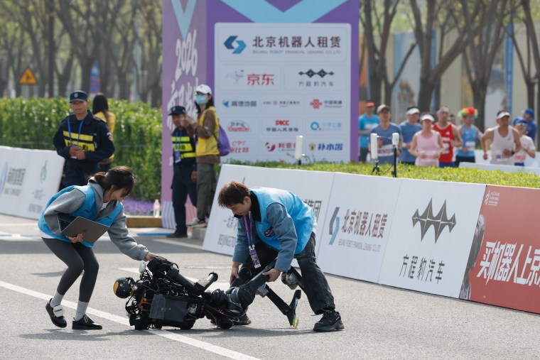 Technicians attend to a humanoid robot after a fall during the Humanoid Robot Half-marathon on Sunday, April 19.