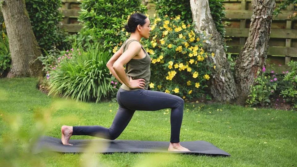  Woman doing glute workout on yoga mat in garden. 