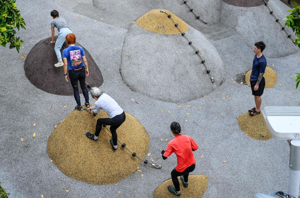This photograph taken on March 17, 2026 shows coach Tan Shie Boon (right) guiding Singaporean elders during a parkour training session in Singapore. Parkour, a discipline that originated in France, focuses on overcoming physical obstacles like walls, gaps and platforms without any aid. — AFP pic 