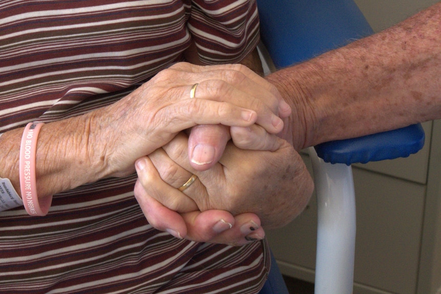 A close shot of a husband and wife holding each others hands.