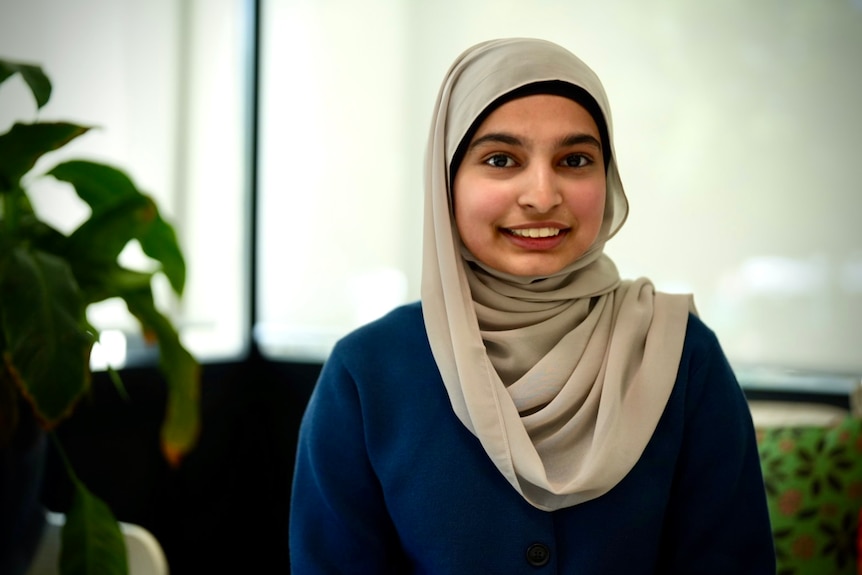 Hafsa wears a headscarf and dark shirt and smiles.
