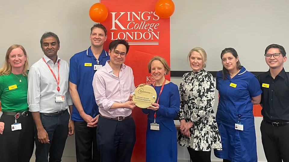 Eight people from King's College Hospital NHS Foundation Trust stand in a row and hold an award.