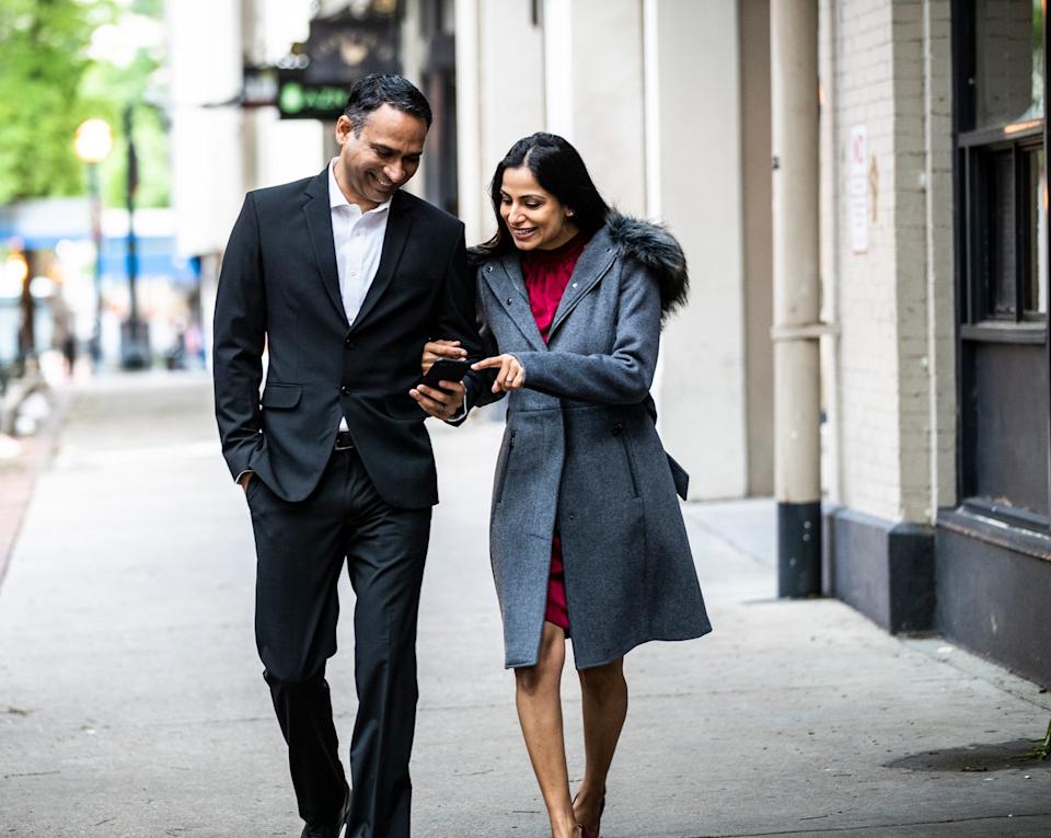 A couple walking and looking at a cell phone.
