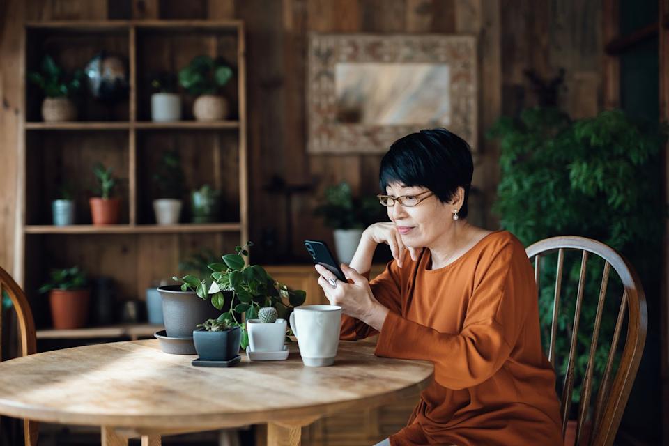 A person looks at a smartphone at a kitchen table.