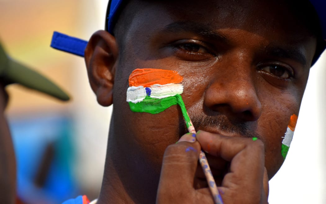 An Indian cricket fan paints his face.