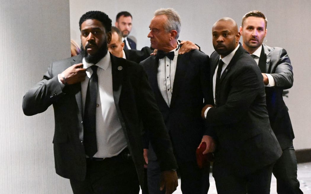 US Secretary of Health and Human Services Robert F. Kennedy Jr. is rushed out by Secret Service agents after loud bangs were heard during the White House Correspondents' dinner at the Washington Hilton in Washington, DC, on April 25, 2026. President Trump is attending the annual gala of the political press for the first time while in office. (Photo by Mandel NGAN / AFP)