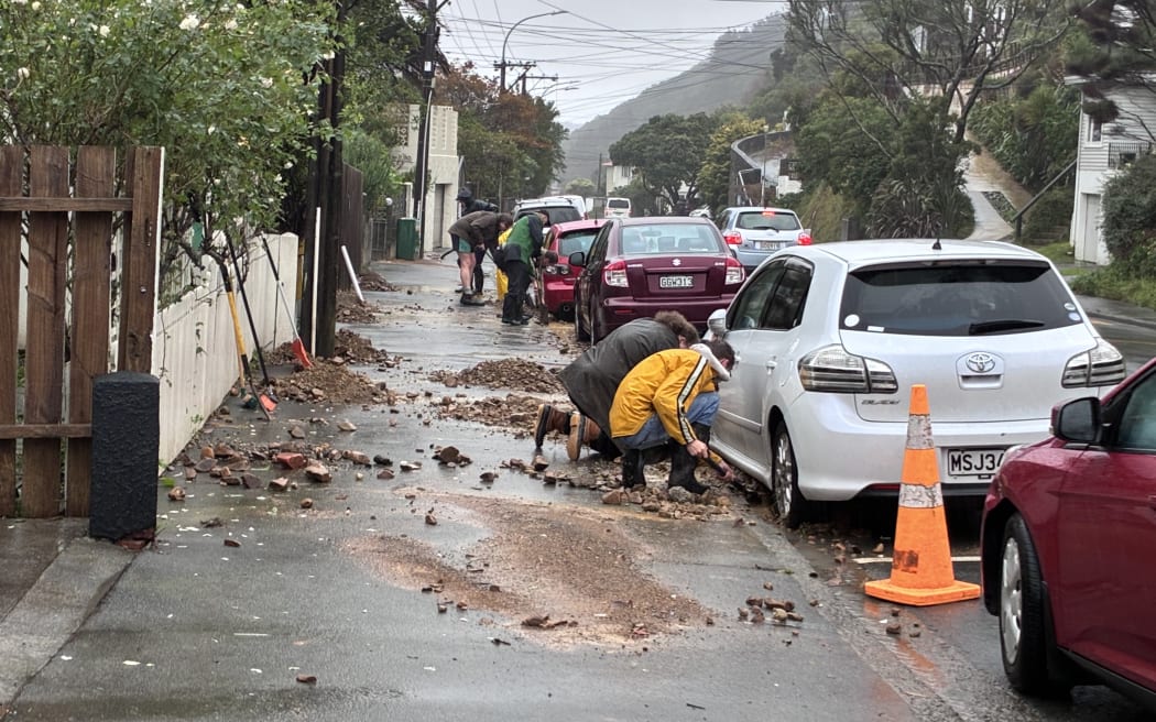 Brooklyn residents clearing gutters of debris from a slip further up the road.