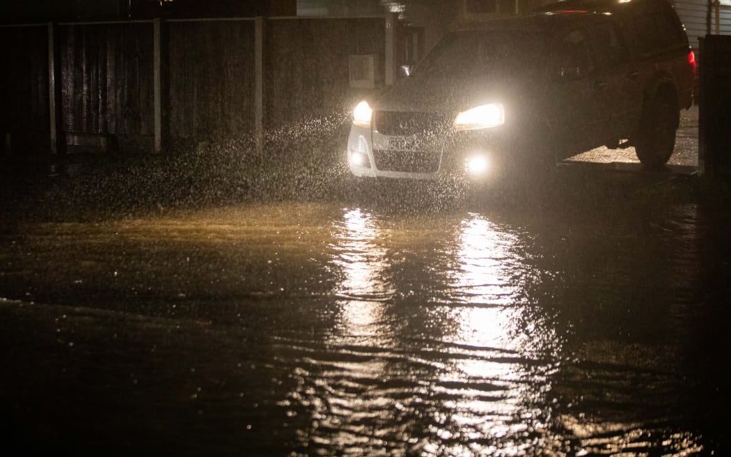 Konini residents evacuating cars as the road floods.
