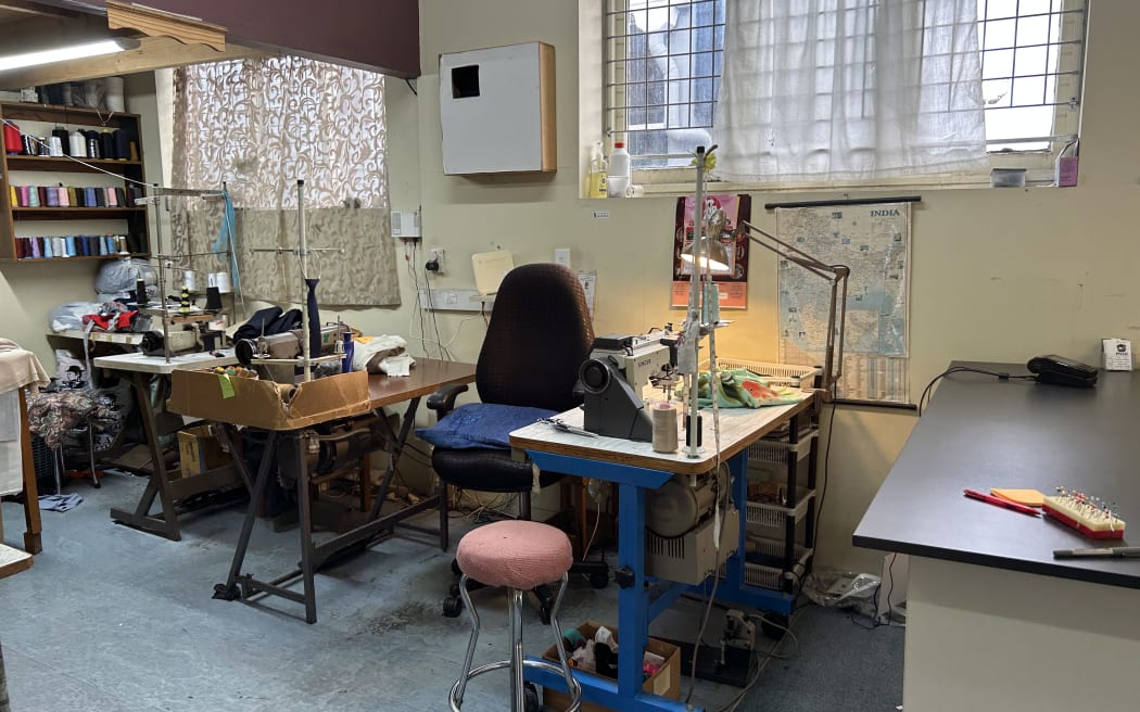Picture depicts a tailor workshop, in it you can see three machines, with colorful threads on one wall.