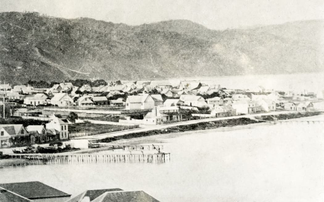 View of  1860s Wellington showing the northern end of Lambton Quay at Pipitea. The intersection with Charlotte Street (now Molesworth Street) is near the centre of the image.