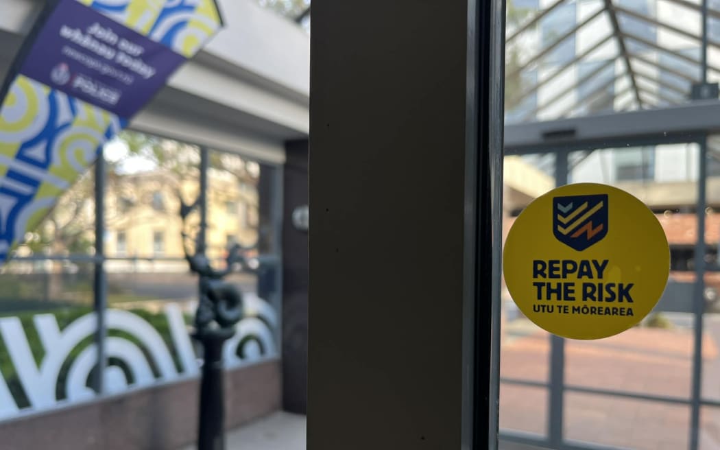 A 'Repay the Risk' campaign sticker inside the Dunedin Central Police Station.