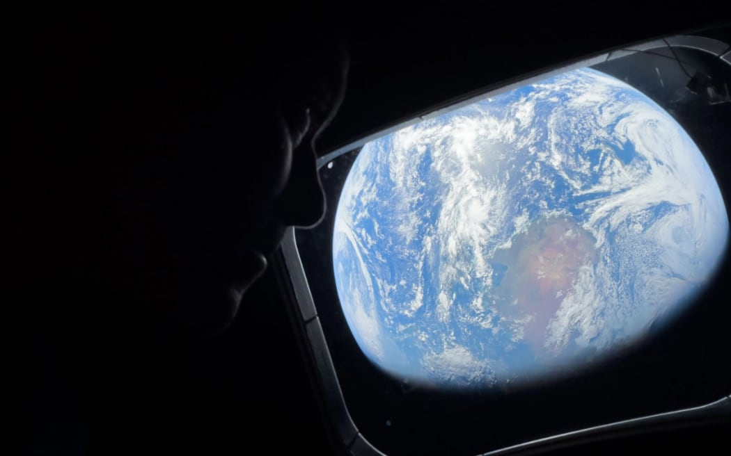 On 4 April, 2026, NASA astronaut and Artemis II Commander Reid Wiseman peers out of one of the Orion spacecraft’s main cabin windows, looking back at Earth, as the crew travels towards the Moon.