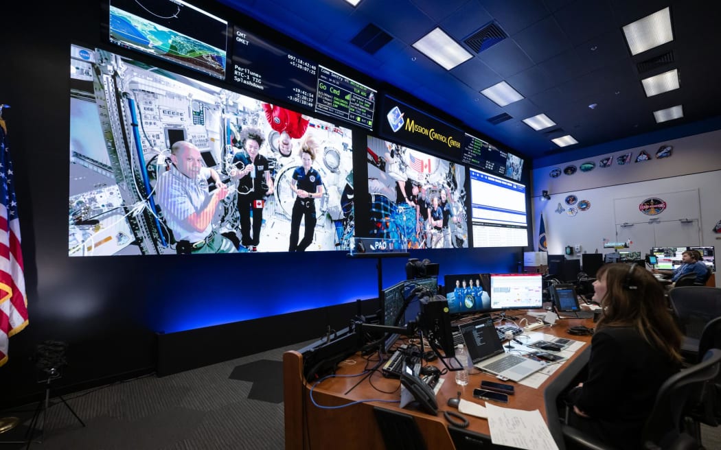 Astronauts on the International Space Station Expedition 74 (left) and Artemis II (right) crews are seen inside the flight control room at NASA's Johnson Space Center in Houston on 7 April , 2026, while the Artemis II crew was on its way back from the Moon.