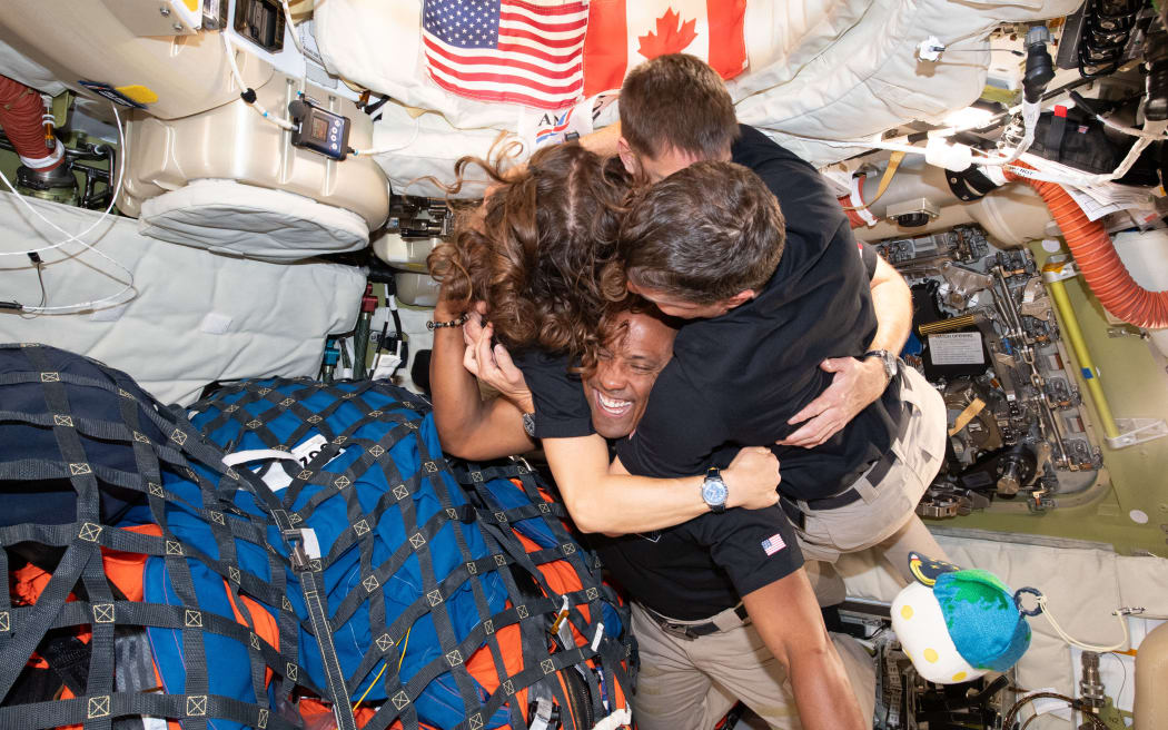 This handout picture released on April 8, 2026, by NASA shows Artemis II crew members Mission Specialist Christina Koch (L), Mission Specialist Jeremy Hansen (top), Commander Reid Wiseman (R), and Pilot Victor Glover (bottom) hugging inside the Orion spacecraft on April 7, 2026. The Artemis II astronauts were jetting towards Earth on April 8 after flying around the Moon -- the first such journey by humans in more than half a century. (Photo by Handout / NASA / AFP) / RESTRICTED TO EDITORIAL USE - MANDATORY CREDIT 