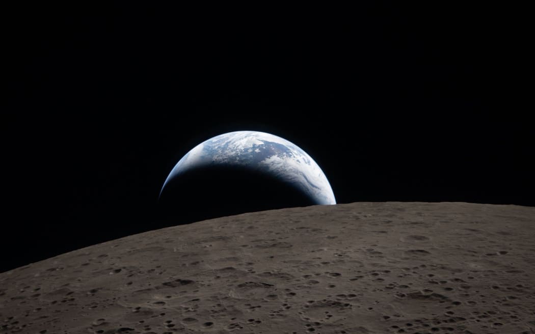 The first mission photo from the far side of the moon, captured from Orion as Earth dips beyond the lunar horizon.