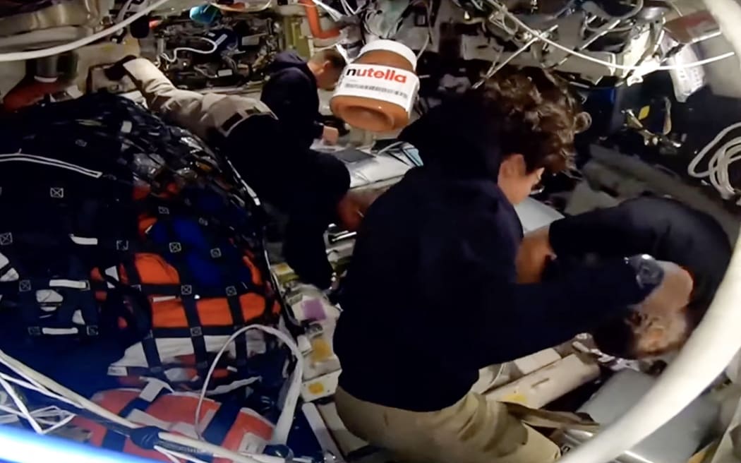 This screengrab from a NASA livestream shows a jar of Nutella floating aboard the Orion spacecraft as Artemis II crew members Victor Glover, Reid Wiseman, Jeremy Hansen and Christina Koch work on April 6, 2026. The four astronauts embarking on NASA's flyby of the Moon became on April 6 the humans to travel furthest from our planet, as they began the lunar observation that is core to their mission. The Artemis II team broke the distance record set by the 1970 Apollo 13 mission, which they are expected to surpass by 4,105 miles (6,606 kilometers) when they reach this journey's anticipated furthest distance from Earth -- 252,760 miles (406,778 kilometers) -- later today. (Photo by Handout / NASA / AFP) / RESTRICTED TO EDITORIAL USE - MANDATORY CREDIT "AFP PHOTO / NASA" - HANDOUT - NO MARKETING NO ADVERTISING CAMPAIGNS - DISTRIBUTED AS A SERVICE TO CLIENTS