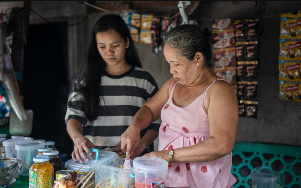 Wallen Robredillo (right) prepares food at her stall in the Baseco slum settlement.