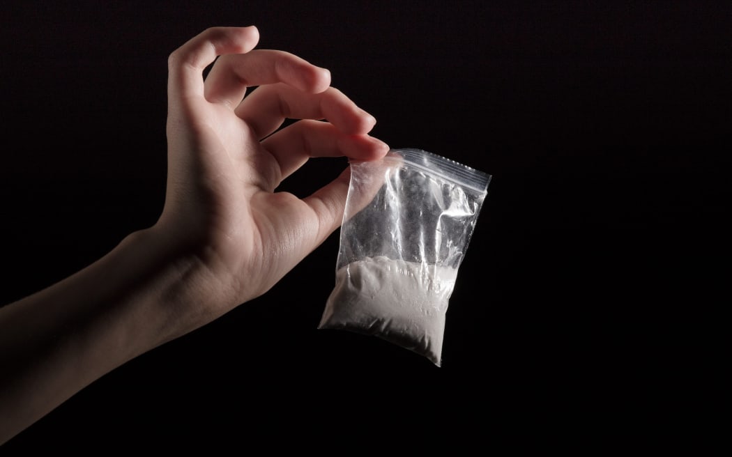 packet with white narcotic in hand on black background