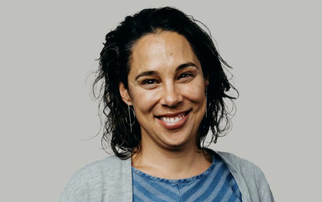 Kristin Ward is a smiling, dark-haired woman wearing a blue striped top and a grey cardigan.