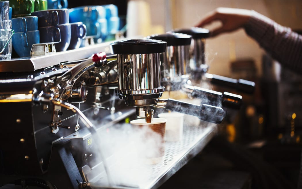 [England] Specialist coffee shop. A person working at a large coffee machine, with three percolating containers, handles and a pipe sending out steam. (Photo by Mint Images / Mint Images / Mint Images via AFP)