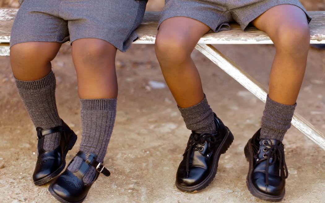 His and her school shoes, toughies on the step. School uniform.