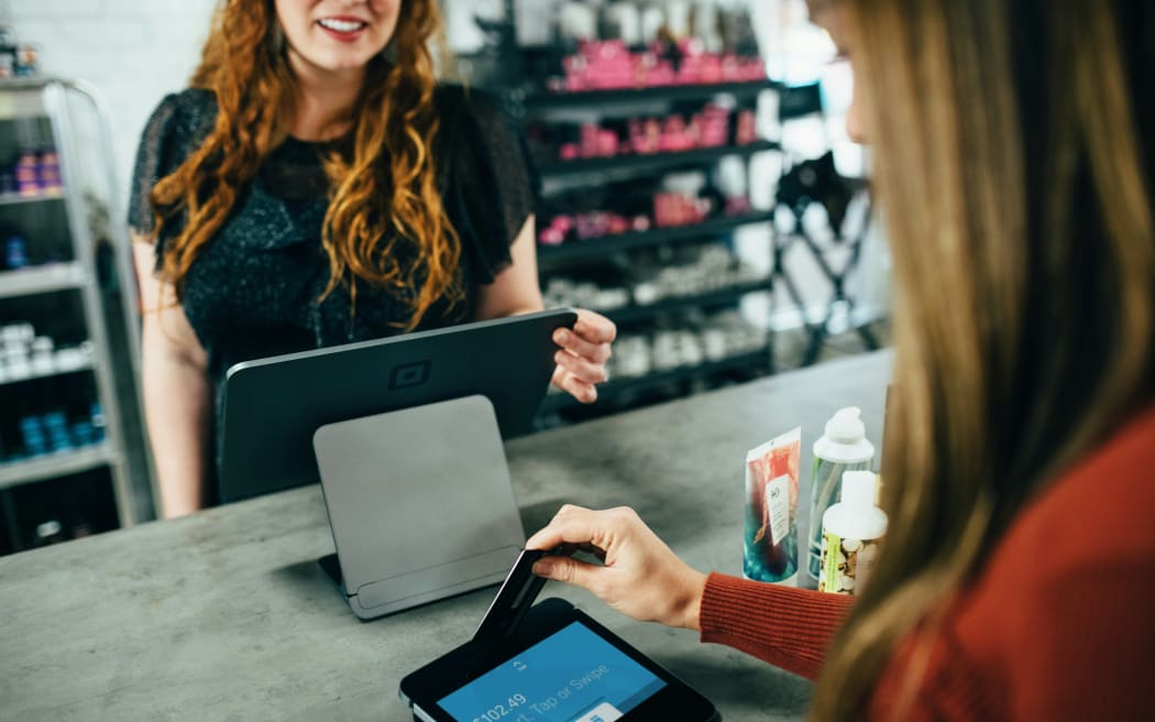 A woman pays for items at a shop counter.