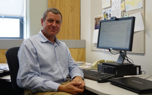 Professor sits in front of screen in his office