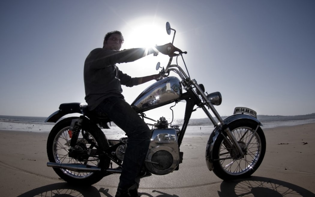 INDIA. MUMBAI CITY. BOMBAY. MOTORCYCLE AT BACK-LIGHTING ON THE BEACH OF BOMBAY