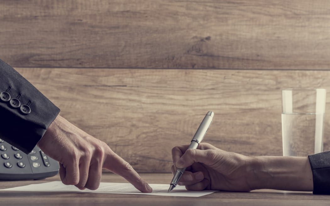 Closeup of employer showing his employee where to sign a contract, with a retro filter effect.
