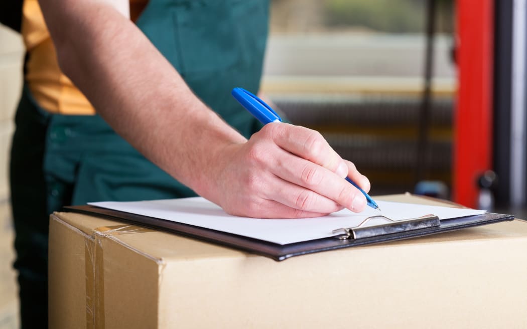 Close-up of a man's hand signing delivery document